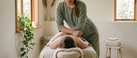 Massage therapist working with her forearm across a client's upper back