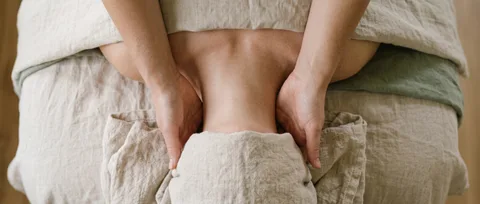 Overhead view of a therapist's hands resting either side of a client's neck